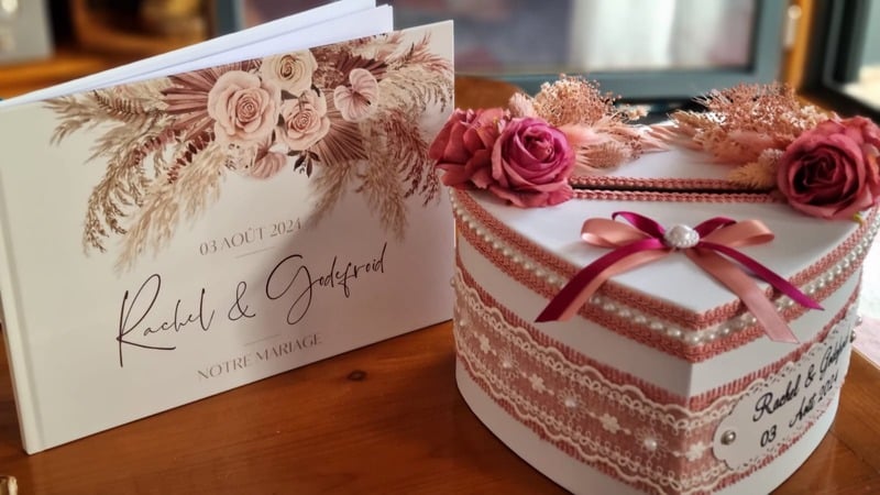 Boîte cadeau avec un carnet sur lequel est inscrit 'Notre mariage', posé sur une table.