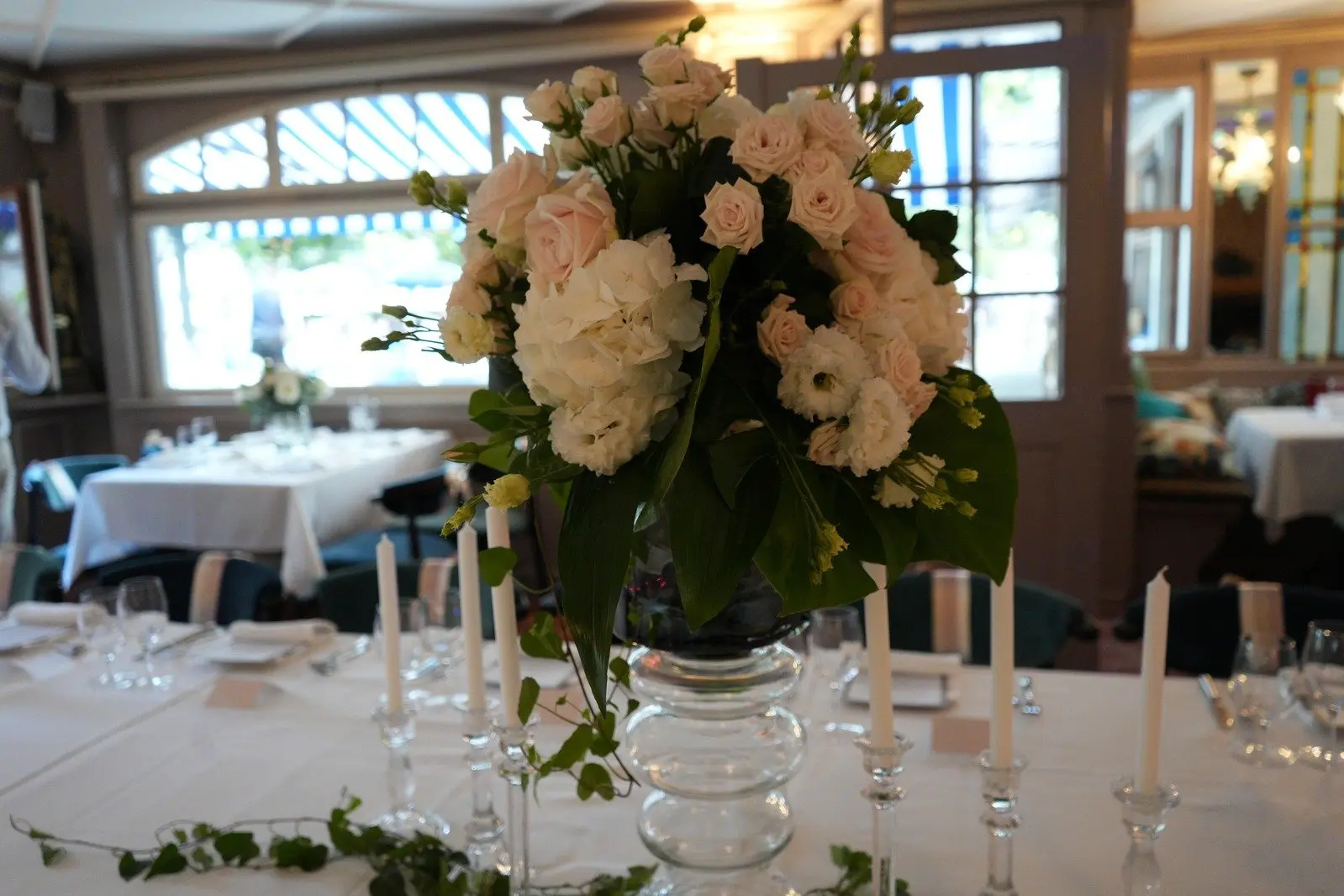 Table de réception décorée avec des bougies et un bouquet de fleurs au premier plan.